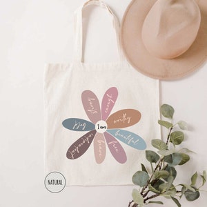 a tote bag with a flower on it next to a hat