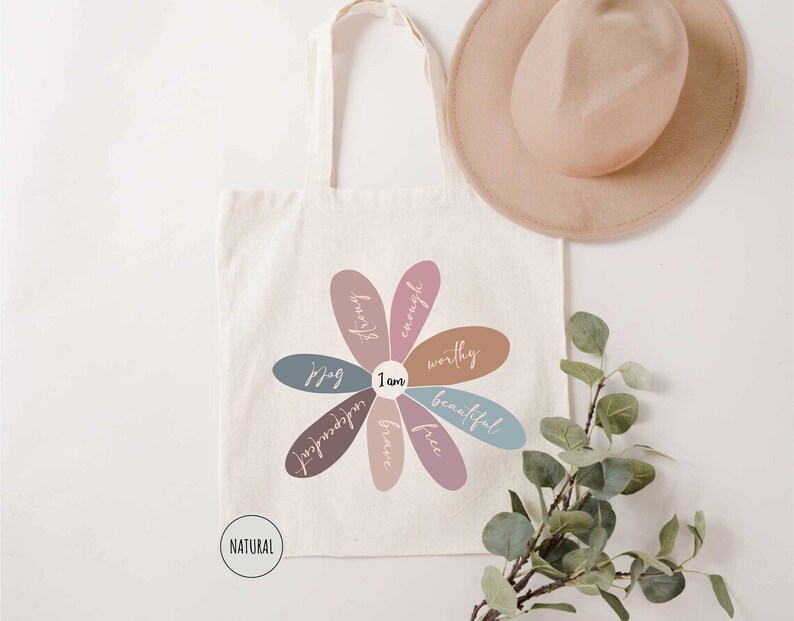 a tote bag with a flower on it next to a hat