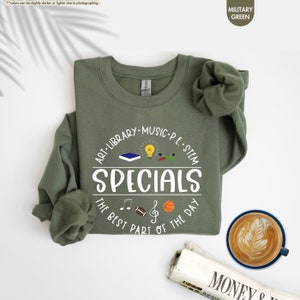 a t - shirt with the words specials on it next to a cup of coffee