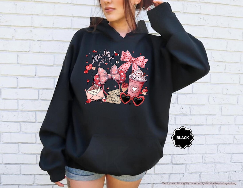 May include: Black hoodie with a graphic design featuring a pink bow, coffee cup, heart-shaped sunglasses, and the text "Literally just a girl." The design includes hearts and an envelope. The hoodie has a front pocket and a hood.