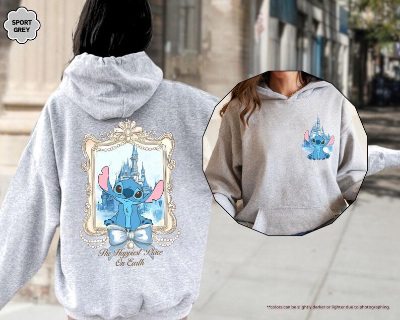 May include: A light grey hoodie featuring a cartoon image of Stitch from Lilo & Stitch. The back of the hoodie has a large framed image of Stitch in front of a castle, with the text "The Happiest Place On Earth". A smaller image of Stitch is on the front.