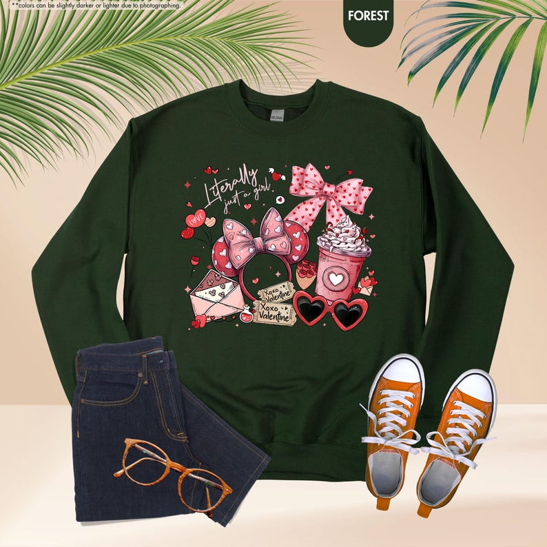 May include: Dark green sweatshirt with the text "Literally just a girl" and Valentine's Day graphics. The image includes a pair of blue jeans, orange trainers, and gold-rimmed glasses.