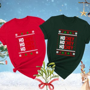 May include: Two Christmas themed t-shirts with a red and green color scheme. The red shirt has the text "HO HO HO HOCKEY" printed on it. The green shirt has the text "HOCKEY HOCKEY HOCKEY" printed on it.