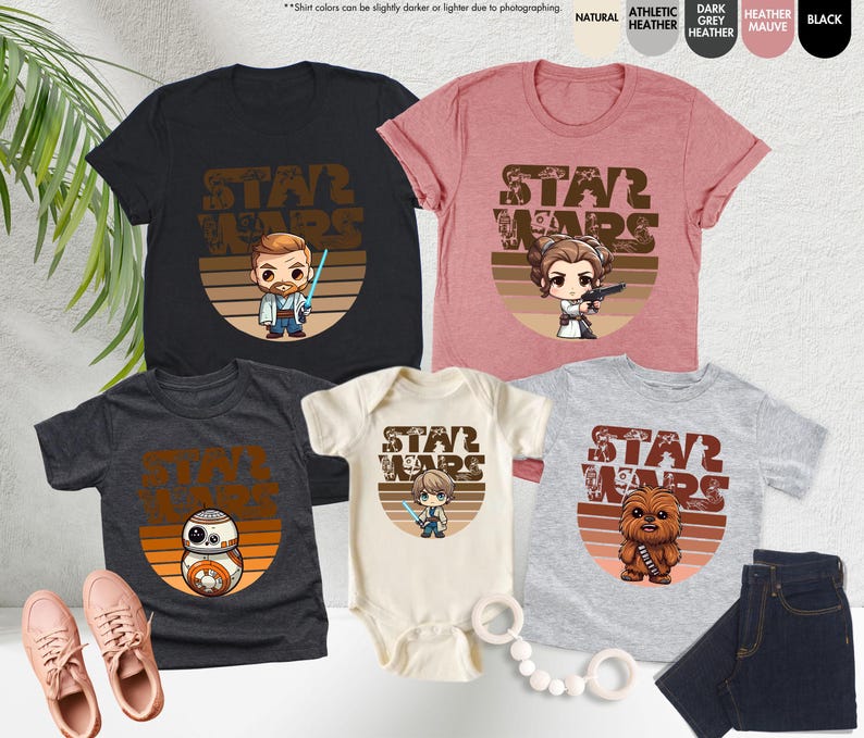 May include: A set of four Star Wars themed t-shirts featuring a retro design with different characters. The shirts are in various colors, including black, heather grey, natural, and pink. The shirts feature the text "Star Wars" and a cartoon character from the Star Wars franchise.