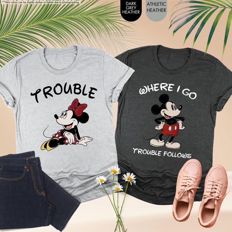 May include: Two graphic t-shirts, one light gray with Minnie Mouse and the word "Trouble", the other dark gray with Mickey Mouse and the words "Where I Go Trouble Follows". Also shown are a pair of jeans and pink sneakers.