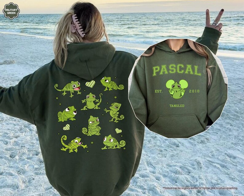 Op de afbeelding: Een olijfgroene hoodie met een cartoonontwerp van Pascal de kameleon uit de film Rapunzel. De achterkant van de hoodie heeft meerdere Pascal-illustraties. De voorkant van de hoodie heeft de naam "PASCAL" en het jaar "2010".