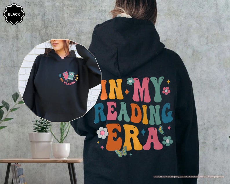 a woman wearing a black hoodie with the words in my reading era printed on