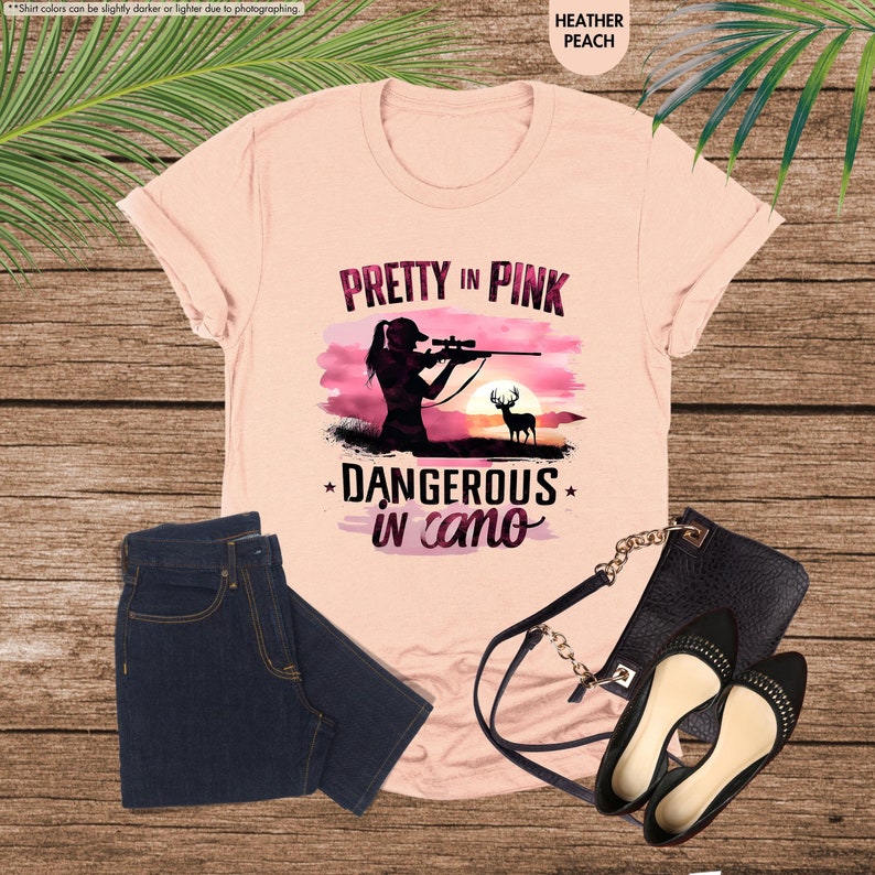 a pink shirt with a picture of a woman holding a gun