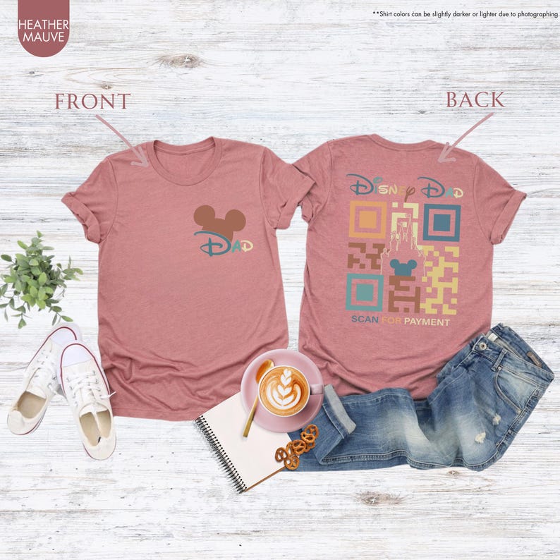 May include: A heather mauve t-shirt with a Disney Dad design. The front of the shirt has a brown Mickey Mouse head with the word "Dad" underneath. The back of the shirt has a stylized QR code with the words "Disney Dad" and "Scan for Payment".