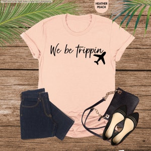 a t - shirt that says we be tripping next to a pair of jeans
