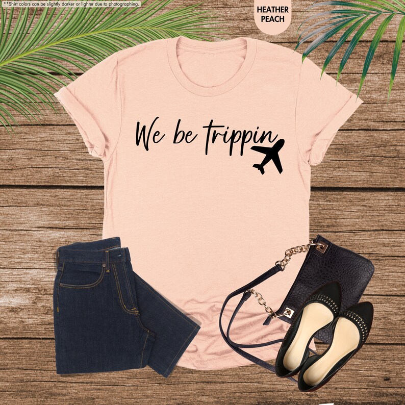 a t - shirt that says we be tripping next to a pair of jeans