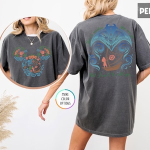 May include: A dark gray t-shirt with a colorful floral design on the front and a blue and green design on the back. The design on the back features a girl in a boat with a wave behind her. The text on the back reads "The Ocean is my happy place".