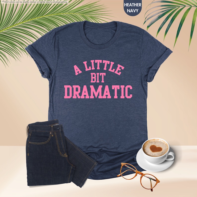 a t - shirt that says a little bit dramatic next to a cup of coffee
