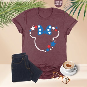 a t - shirt with a mickey mouse head on it next to a cup of