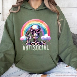 a woman sitting on a couch wearing a green hoodie