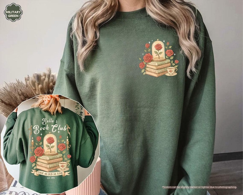 Puede incluir: Sudadera verde militar con un gr&aacute;fico de una rosa en una c&uacute;pula de cristal sobre libros, rodeada de rosas rojas y una taza de t&eacute;. La parte trasera de la sudadera muestra el texto "Belle's Book Club" y "Tale as Old as Time."