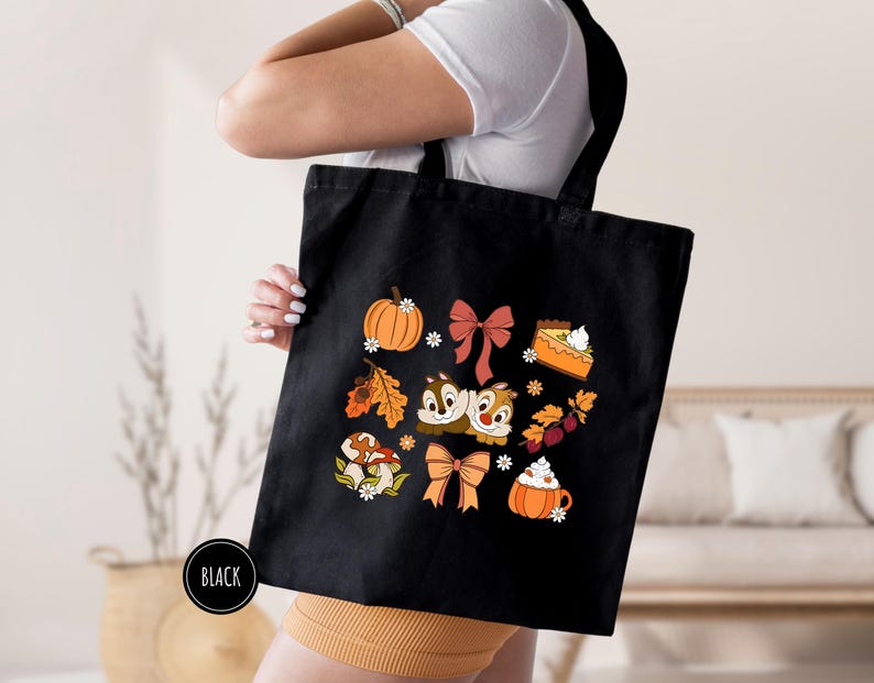 a woman holding a black bag with a bunch of cats and pumpkins on it