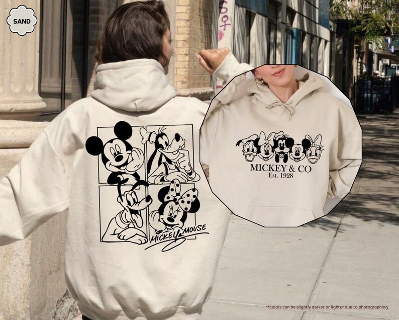 May include: Sand-colored hoodie featuring Mickey Mouse and friends in black and white graphics. The back displays Mickey, Goofy, and Minnie Mouse, while the front showcases the text "Mickey & Co. Est. 1928".