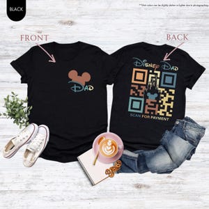 May include: Black t-shirt with a Mickey Mouse head and the word "DAD" on the front. The back of the shirt has a colorful QR code with the words "Disney Dad" and "Scan for Payment".