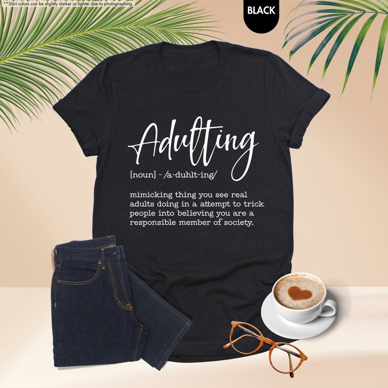 a t - shirt with the words adulting on it next to a cup of