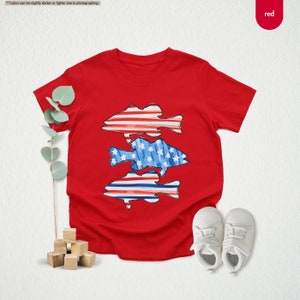 a red t - shirt with a blue fish on it next to a pair of