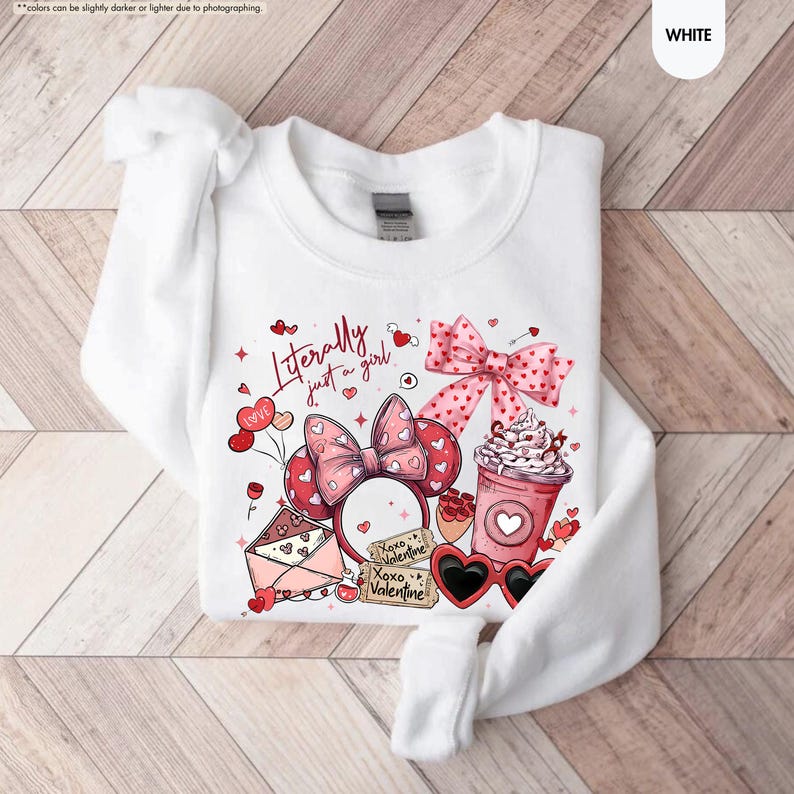 May include: White sweatshirt featuring a Valentine's Day design. The graphic includes a pink bow, heart-shaped sunglasses, a coffee cup, and the text "Literally just a girl." The sweatshirt has a crew neck and long sleeves.