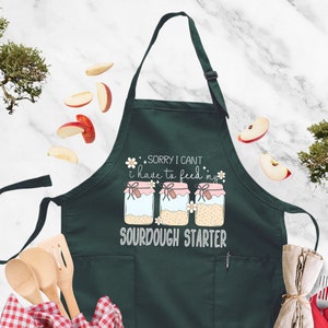 a green apron that says sorry i can't have to drink sourdough