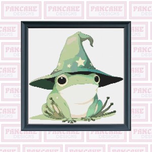 May include: A green frog wearing a blue and green wizard hat with a white star on the hat. The frog is wearing a white face mask.