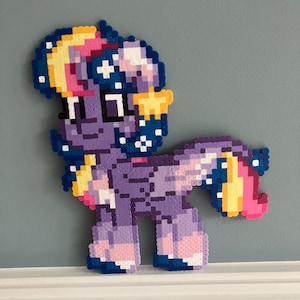May include: A purple and blue pixel art pony with a yellow and pink mane and tail. The pony has a star on its forehead and a crescent moon on its head. The pony is standing on a white surface.