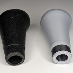 May include: Two gear shift knobs, one black leather and one gray plastic. Both have a black ring around the base.