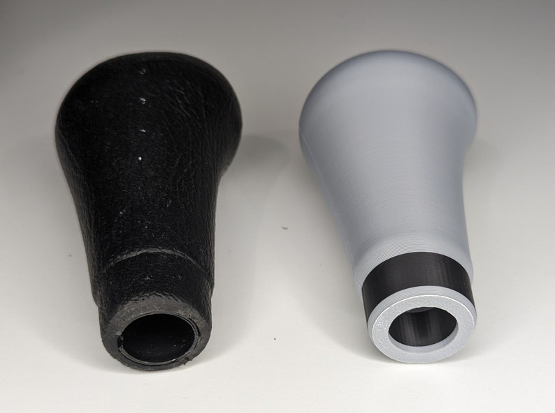 May include: Two gear shift knobs, one black leather and one gray plastic. Both have a black ring around the base.