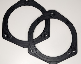 May include: Two black plastic speaker rings, likely for car audio, with a hexagonal shape and multiple small holes.