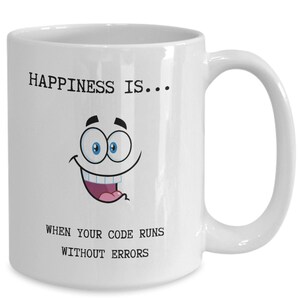 Peut inclure: Mug en céramique blanche avec un visage de dessin animé et le texte "HAPPINESS IS... WHEN YOUR CODE RUNS WITHOUT ERRORS". La tasse a une grande anse et un visage souriant avec des yeux bleus et une bouche rose.