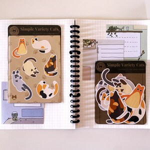 May include: Two sheets of stickers featuring illustrations of cats in various poses. The stickers are on a brown background with the text "Simple Variety Cats" and "Stickers by the Cat Market".