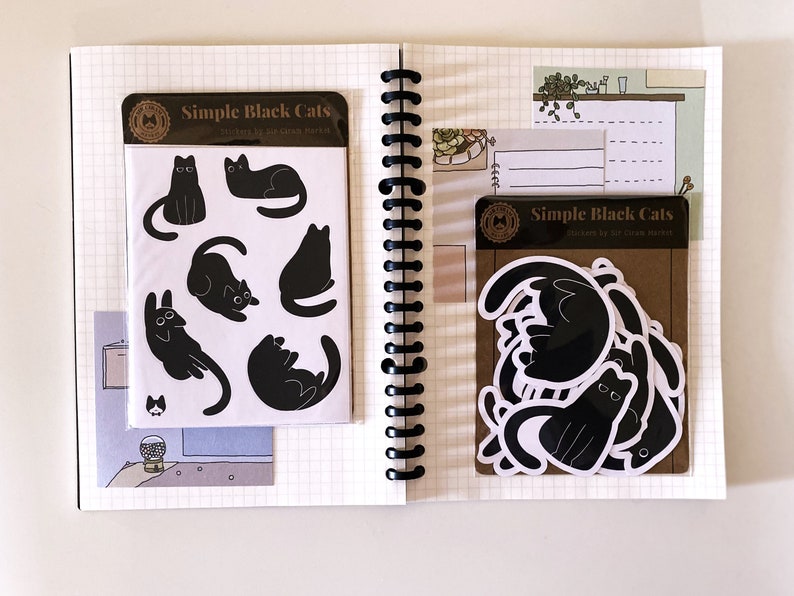 May include: Two sheets of stickers featuring black cats in various poses. The stickers are labeled "Simple Black Cats" and are packaged in a clear plastic sleeve.