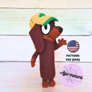 Puede incluir: Patrón de amigurumi de crochet para un dachshund marrón que lleva una gorra de béisbol amarilla y verde. El patrón está disponible en formato PDF y está escrito en inglés. El patrón está disponible para su compra en Etsy.