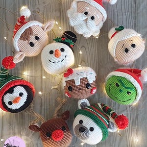 Puede incluir: Una colección de adornos navideños hechos a mano con ganchillo, que incluyen a Papá Noel, un muñeco de nieve, un pingüino, un hombre de jengibre, un reno, un oso polar y el Grinch. Los adornos son de varios colores y estilos, con la palabra "Welcome" en la imagen.