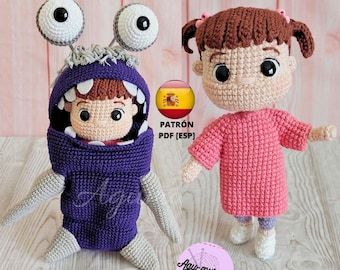 May include: Two crocheted plush toys, one dressed as a purple monster with one eye and the other dressed as a pink-clad girl with brown hair. The text "PATRÓN PDF [ESP]" is visible in the image.