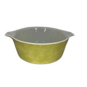 May include: A round, lime green glass bowl with two integrated side handles. The exterior features a textured, mottled finish in a vibrant green hue, while the interior is smooth, glossy, and white. The bowl has a wide, open top design.