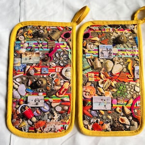 May include: A pair of yellow pot holders with a colorful beach scene design. The pot holders feature seashells, starfish, and other beach-themed items.