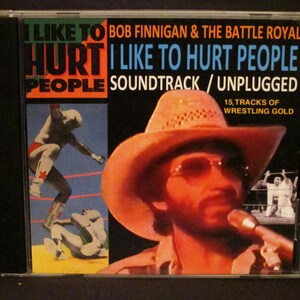May include: A CD case with a black background and a colorful image of a wrestler in a red and white outfit. The text on the case reads "I Like To Hurt People Soundtrack / Unplugged" and "Bob Finnegan & The Battle Royal".
