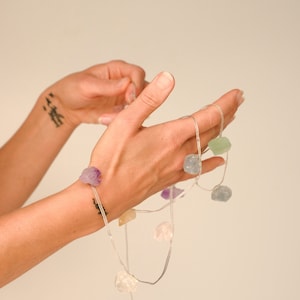 Puede incluir: Una cadena de luces con cable transparente y bombillas con forma de cristal de varios colores. Los cristales son en tonos de morado, verde, amarillo y transparente.