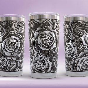 Puede incluir: Tres vasos de acero inoxidable con un diseño floral negro y plateado. Los vasos presentan un fondo negro con un patrón floral plateado de rosas y hojas.