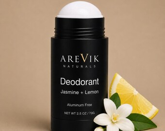 Könnte beinhalten: Ein schwarzer, zylindrischer Deodorant-Stick mit weißem Applikator. Das Etikett zeigt AREVIK NATURALS, Deodorant, Jasmine + Lemon, Aluminum Free und NET WT 2.5 OZ / 70G. Eine weiße Jasminblüte und eine gelbe Zitronenscheibe liegen davor.