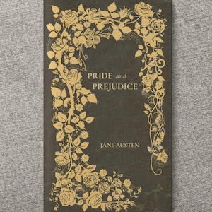 Puede incluir: Una cubierta de libro verde oscuro con adornos florales dorados y el título "PRIDE and PREJUDICE" de Jane Austen. La cubierta tiene una estética vintage, con un borde decorativo de rosas y hojas.