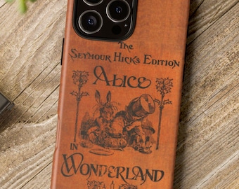 Può includere: Una custodia per telefono marrone con la copertina di "Alice nel Paese delle Meraviglie" di Seymour Hicks. Il design include illustrazioni del Bianconiglio e altri personaggi, con il testo del titolo in stile vintage. La custodia è su una superficie di legno.