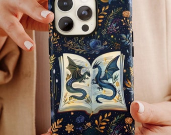 May include: A dark blue phone case featuring a fantasy illustration. The design includes an open book with two dragons, surrounded by floral and celestial elements. The case has a black border and a camera cutout.