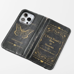 May include: Black leather phone case with a gold butterfly design and the text "LIMITED EDITION". The inside features a gold-framed panel with the text "[YOUR NAME'S] Book of Shadows: A Grimoire of Secrets".