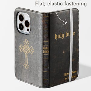 May include: A gray and black leather phone case with a gold cross design and the words "holy bible" in gold lettering. The case has a flat, elastic fastening and a space for initials.