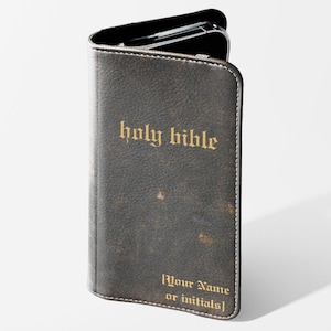 May include: A dark brown leather phone case with the words "holy bible" in gold lettering. The case has a distressed look and a white stitched border. The bottom of the case reads "[Your Name or initials]"